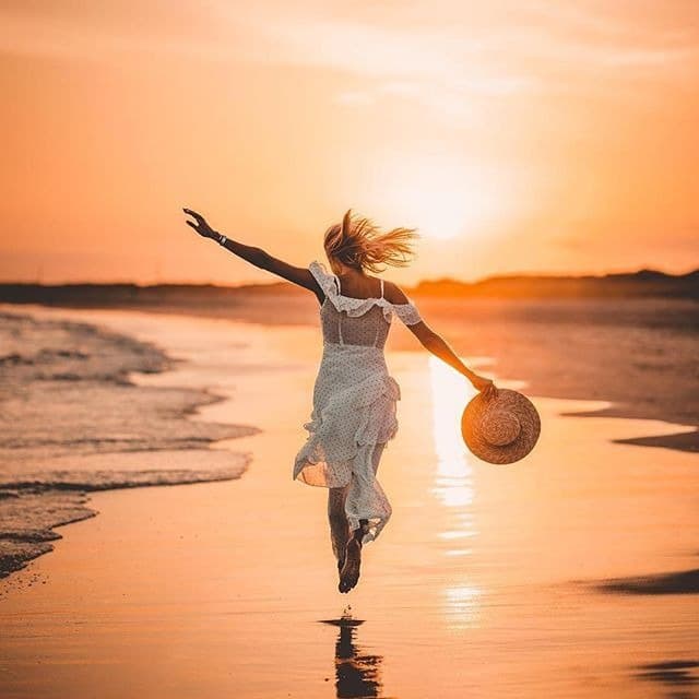 Mulher livre correndo na praia ao pôr do sol